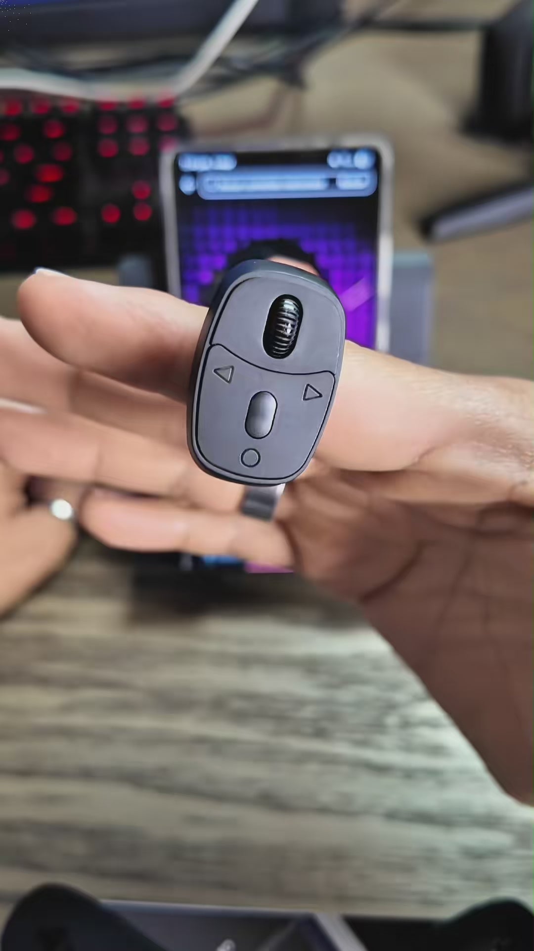 A hand wearing the FlickRing remote, scrolling a phone with a thumb press.